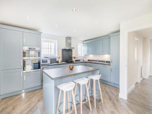 a kitchen with blue cabinets and a island with stools at Silkstone Crescent in Buxton