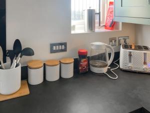a kitchen counter with four white trash cans on it at Silkstone Crescent in Buxton +25 photos