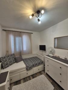 a bedroom with a bed and a dresser with a television at Apartman Prošperino in Vis