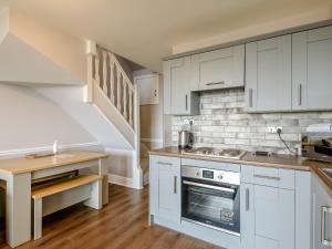 a kitchen with white cabinets and a staircase at Cottage 2 - Uk38222 in Ashby cum Fenby
