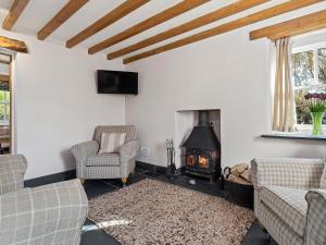 a living room with a fireplace and a couch and chairs at Temple House in Abercastle