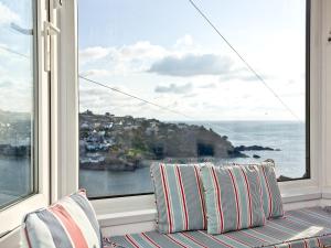 a room with a window with pillows and a view of the ocean at Anchor Loft in Fowey