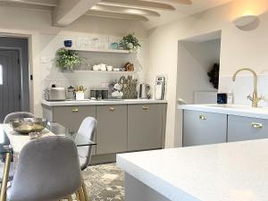 a kitchen with gray cabinets and a table and chairs at Restwell in Mundesley