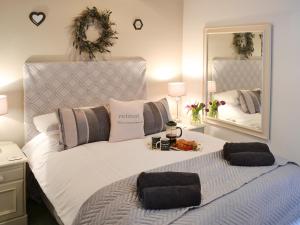 a bedroom with a large white bed with a mirror at Restwell in Mundesley +3 photos