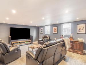 a living room with couches and a flat screen tv at Riversdelle in Beccles