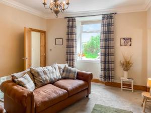 a living room with a brown couch and a window at Inveravon Cottage in Polmont