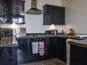 Una cocina con gabinetes negros y un horno de estufa. en Beauty Abounds, en Morecambe 8 fotos más