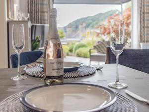 Una botella de vino sobre una mesa con dos copas. en River Coombe, en Dartmouth