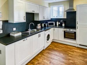 a kitchen with white cabinets and a sink and a dishwasher at Muckle Green Holm - Uk48091 in Kirkwall