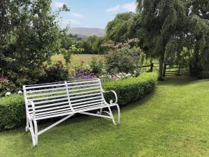 a white bench sitting in the grass in a garden at Calico Cottage in Hope