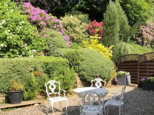 a table and chairs in a garden with flowers at Calico Cottage in Hope