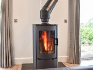 a stove with a fire in a room at The Oaks in Great Strickland