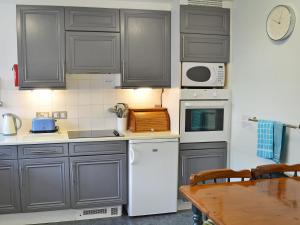 a kitchen with gray cabinets and a white refrigerator at Spinnakers in Falmouth