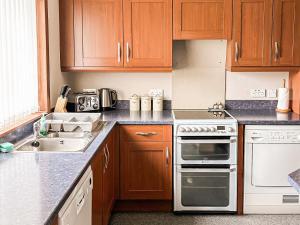 a kitchen with wooden cabinets and a white stove top oven at Havrock in Kirkwall