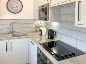 a white kitchen with a sink and a microwave at Hop Cottage in Sellindge