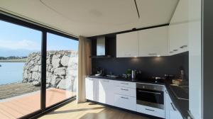 a kitchen with white cabinets and a view of the water at Laguna Houseboat in Rome