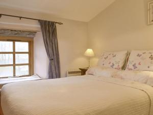 a bedroom with a large white bed with a window at St Francis Cottage in Seathwaite +6 photos