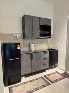 cocina con nevera negra y microondas en MelDy Guest House 3BR Tol Nilai with pool, en Nilai