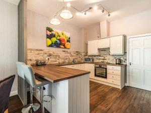 a kitchen with white cabinets and a painting of fruit at Cottage 9 - Uk38220 in Ashby cum Fenby