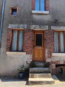 a brick house with a wooden door and stairs at La Petite Sancerroise in Jars