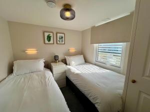 ein Schlafzimmer mit zwei Betten und einem Fenster in der Unterkunft Beach Cottage 6 - Bright & Modern By the Sea in Westward Ho