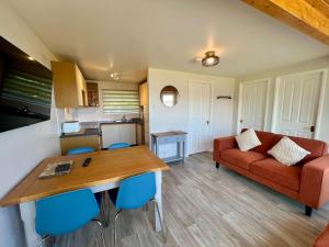 ein Wohnzimmer mit einem roten Sofa und einem Tisch in der Unterkunft Beach Cottage 6 - Bright & Modern By the Sea in Westward Ho