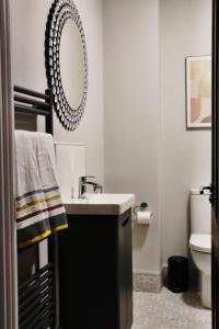 ein Badezimmer mit Waschbecken und Spiegel an der Wand in der Unterkunft The Grey Door 2 Bed Cottage Banbridge Parking Private Garden l WeStay Belfast Short Lets And Serviced Accommodations in Banbridge + 36 Fotos