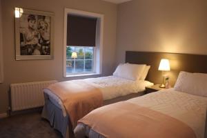 ein Hotelzimmer mit zwei Betten und einem Fenster in der Unterkunft The Grey Door 2 Bed Cottage Banbridge Parking Private Garden l WeStay Belfast Short Lets And Serviced Accommodations in Banbridge