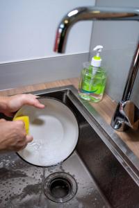 a person washing a plate in a sink at Tiny Away Escape at Lazarus - 2017 in Singapore
