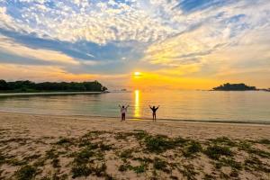 two people standing on a beach with their arms up at Tiny Away Escape at Lazarus - 2017 in Singapore