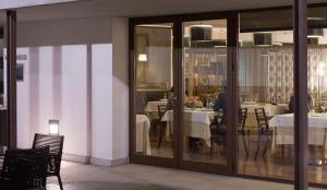 un restaurante con puertas y mesas de cristal y una persona sentada en una mesa en Hotel Convento Aracena & SPA en Aracena