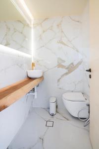 a white bathroom with a toilet and marble walls at Grypes Deluxe Complex in Egina