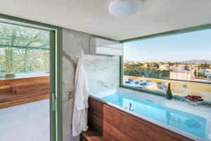 爱琴娜岛Grypes Deluxe Complex的一间带蓝色浴缸和窗户的浴室