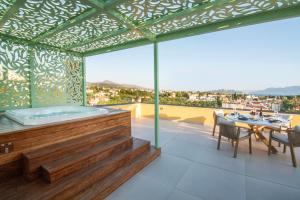 a balcony with a hot tub and a table and chairs at Grypes Deluxe Complex in Egina