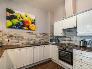 a kitchen with white cabinets and a painting on the wall at Cottage 9 - Uk38220 in Ashby cum Fenby