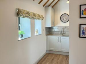a kitchen with white cabinets and a window with a sink at Hop Cottage in Sellindge