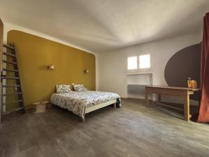 ein Schlafzimmer mit einem Bett und einem Tisch und einem Fenster in der Unterkunft Elégante Maison de Village in Ortaffa