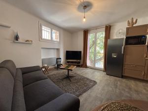 ein Wohnzimmer mit Sofa und eine Küche in der Unterkunft Elégante Maison de Village in Ortaffa