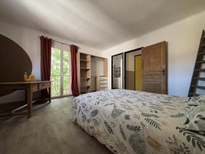 ein Schlafzimmer mit Bett, Schreibtisch und Fenster in der Unterkunft Elégante Maison de Village in Ortaffa