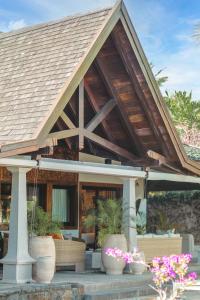 a house with a wooden roof with some flowers at Villa Matahari by muse villas in Rivière Noire