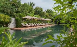 a swimming pool with lounge chairs and umbrellas at Khmer House Resort in Siem Reap