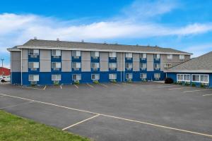 a large blue and gray building with a parking lot at Super 8 by Wyndham Osseo WI in Osseo