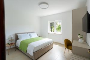 a white bedroom with a bed and a window at Sorrento Realty Holidays - Sunrise and Sunset Sorrento Coast in Meta