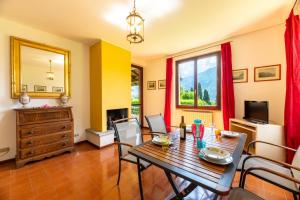 a dining room with a table and chairs and a television at Antica Isola Giardino - Happy Rentals in Sala Comacina