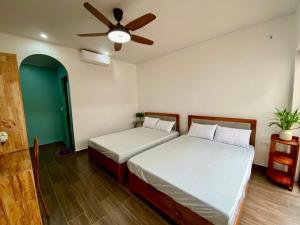 une chambre avec deux lits et un ventilateur de plafond dans l'établissement Euphoria Cat Ba Homestay, à Cat Ba 9 autres photos