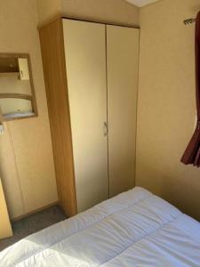a bedroom with a closet and a bed with white sheets at Lovely Dog Friendly 8 Berth Caravan At Sunnydale, Lincolnshire Ref 35197S in Louth +6 photos