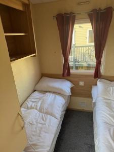 two beds in a small room with a window at Lovely Dog Friendly 8 Berth Caravan At Sunnydale, Lincolnshire Ref 35197S in Louth