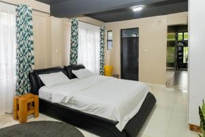 a bedroom with a large bed with white sheets at Elmadel Coffee Gardens 5Bedroom Villa Mua Hills 50kms from Nairobi in Machakos