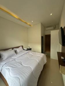 a large white bed in a room with a television at bali thousand island living - guest house in Pesanggaran