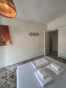 a white bedroom with two white towels on a bed at Summer Holidays in Nea Kalikratia
